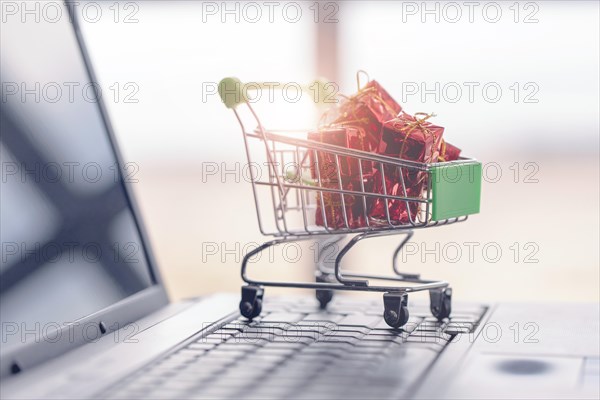 Gift boxes in a shopping cart on a laptop keyboard.