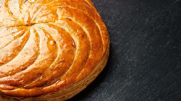 Epiphany cake or galette des rois in French on black slate background