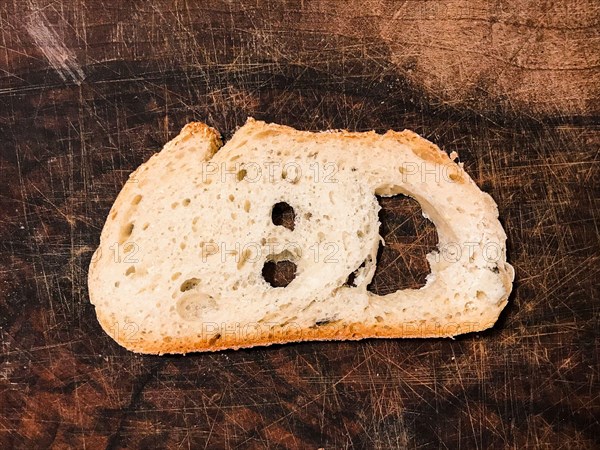 Slice of rustic rustic white bread in the shape of a smiling face on in wooden cutting board