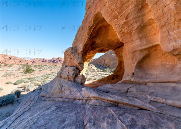 Close-up view through ancient rock formation in Valley of Fire with canyon in background.