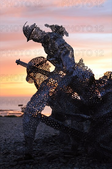 Life size sculptural figure in the D-Day 75 Garden in Arromanches-les-Bains, France at Sunset. The installation was first created by John Everiss for