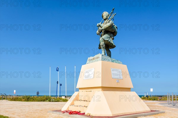 Statue to WWII British commando and piper Bill Millin playing the pipes in kilt, by sculptor Gaetan Ader, erected on Sword beach, Normandy, in 2013.