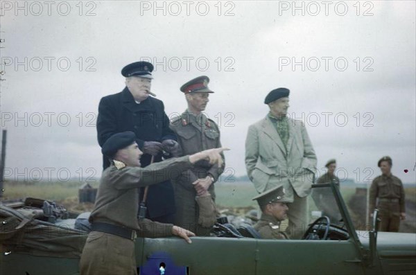 The Visit of the Prime Minister, Winston Churchill To Caen, Normandy, 22 July 1944 The Commander of the 2nd Canadian Corps, Lieutenant General G G Simonds pointing out a section of the front to Mr Churchill. Also standing in the car are the Commander of the British 2nd Army, Lieutenant General Sir Miles Dempsey and the Commander of the 21st Army Group General Sir Bernard Montgomery.