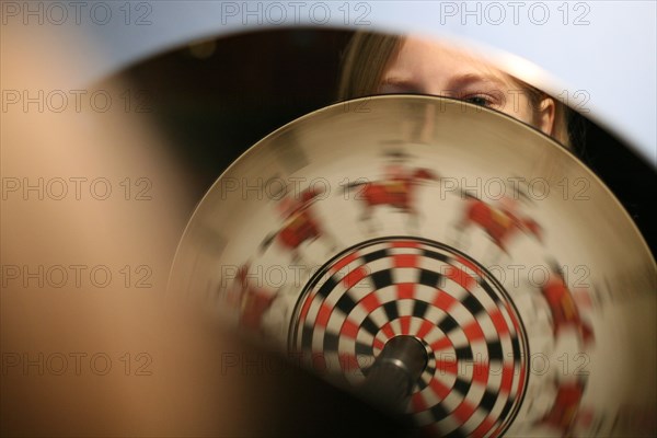 Young visitor examines a phenakistoscope, an early animation device, in the Deutsches Technikmuseum Berlin, Germany.