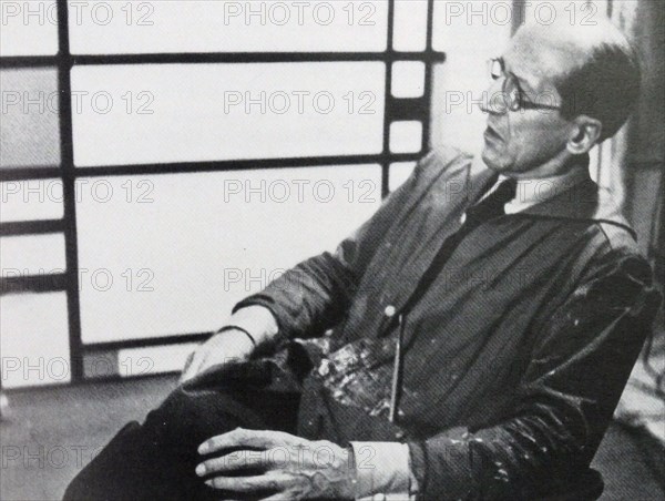 Photograph of the famous Dutch artist Piet Mondrian (7th March 1872 - 1st February 1944). He is shown seated infront of one of his pieces of work. The photograph was taken around 1942.