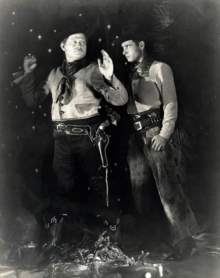 Silent film scene still. Two cowboys, one with a gun to ther other's back, 1930.  File Reference # 1183_012THA