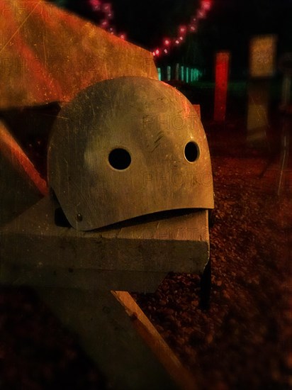 A helmet sitting on a bench in the dark resembles a face.