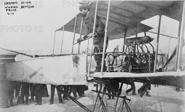 Farman after winning Deutsch prize, Henri Farman, full-length portrait, standing at wheel of airplane, facing left., 1911(?), Farman, Henri, 1873, Photographic prints, 1910-1920., Portrait photographs, 1910-1920, Photographic prints, 1910-1920, 1 photographic print