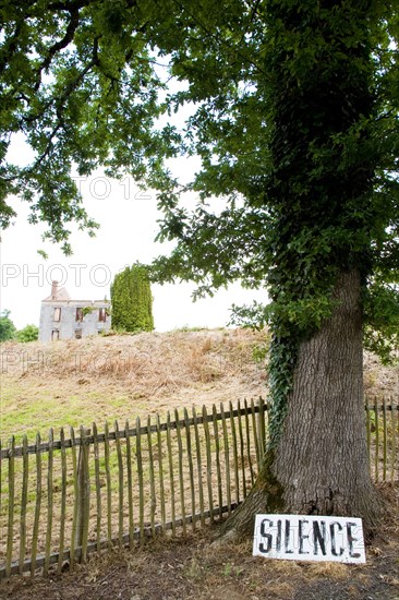 The destroyed French village Oradour-sur-Glane. It's entrance has a sign requesting silence resting against an oak tree.