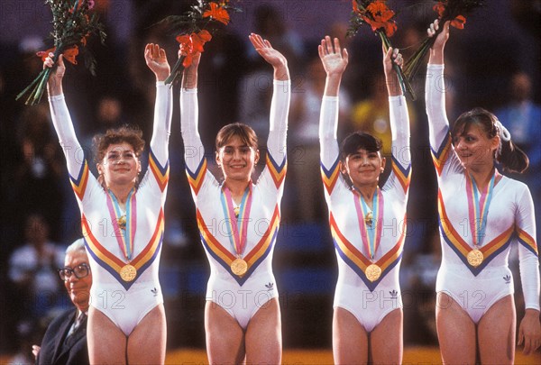 Romanian Gymnastics Team stands on victory stand with gold medals for winning team competition at 1984 Olympic Games in LA