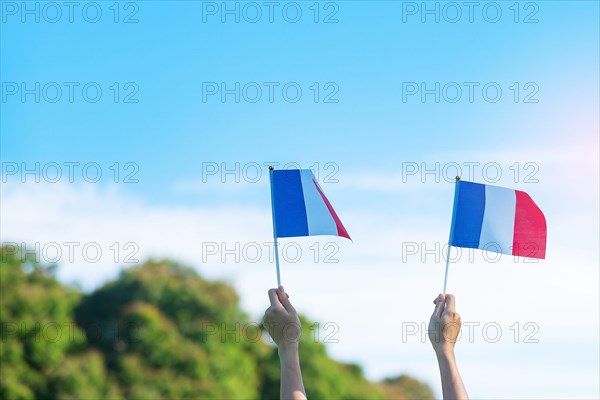 hand holding France flag on blue sky background. holiday of French National Day, Bastille Day and happy celebration concepts