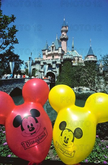Brightly-colored balloons with the face of Mickey Mouse float in front of Sleeping Beauty Castle, an imposing fairy-tale structure that is the centerpiece of the world’s most famous theme park, Disneyland, which opened in 1955 in Anaheim, California, USA. The building was modeled after a real castle, Neuschwanstein, constructed in Germany in the late 1800s as a palace for King Ludwig II of Bavaria. Disneyland was the creation of Walt Disney, a well-known American entrepreneur and filmmaker who created Mickey Mouse and other iconic cartoon characters.