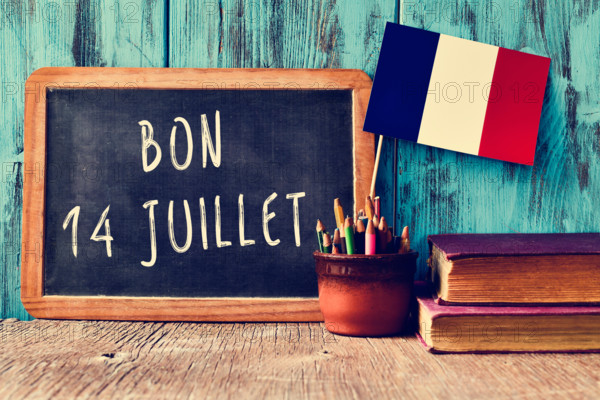 a wooden-framed chalkboard with the text bon 14 juillet, happy 14th of July, the National Day of France, written in French and a