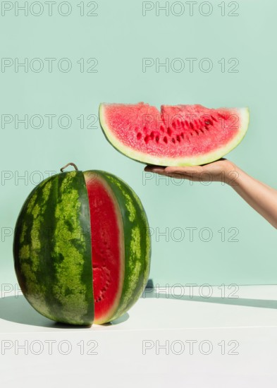 Ripe fresh watermelon on neo mint colored background. Woman's hand holding slice of watermelon.Creative minimal summer fruit concept.