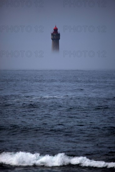The dramatic La Jument lighthouse, shrounded in summer fog, off the coast of the Ile d'Ouessant, Brittany. The iconic 47-metre high lighthouse was bui