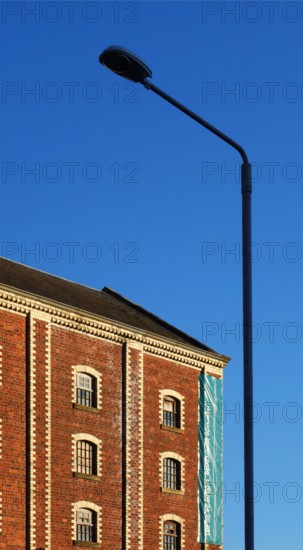 A classic street lantern embraces a stone building with bricks, against the background of the blue sky, Greenock, Scotland