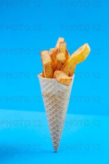 French fries bouquet in a ice cream cone on blue background. Fast food, street food concept.