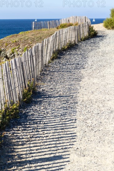 Typical french coast sea view with a pathway to the beach and wooden fence creating beautiful shadow.