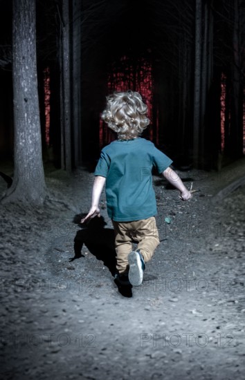 A little boy runs through the night forest after an orange light