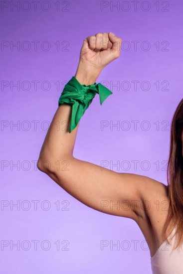 Close up of an arm with a closed fist wearing a green scarf as a symbol of the struggle for the legalization of abortion in Argentina