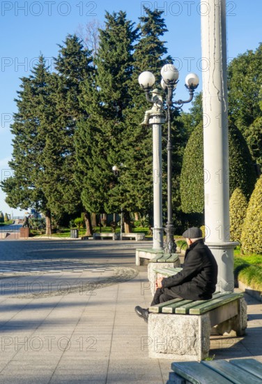 A lonely man sits on a park bench. An elderly gentleman in the park. Relaxation in the park. Loneliness concept