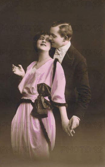 Vintage hand-coloured photograph of a romantic couple embracing. Adapted from an old postcard.