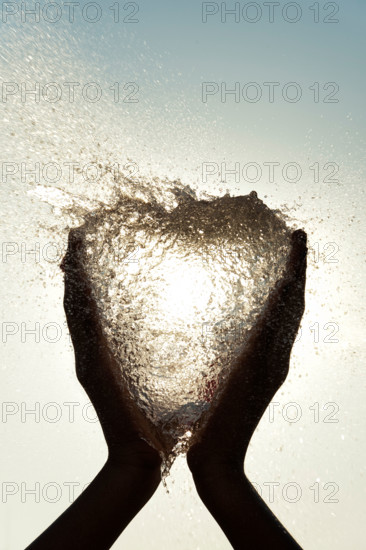 Indian girls hands holding a heart shaped burst water balloon. India