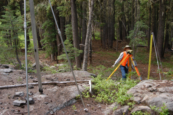 A USGS team conducts a leveling survey on a volcanic mountain on August 24, 2006. The process involves precise measurements to monitor any changes in the landscape due to seismic activity or geological shifts.