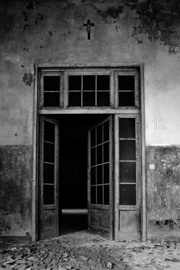 Italy. Abandoned hospital door with cross on the wall