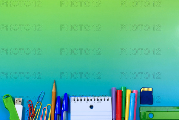 School or office supplies as a low border on a blue green background with copy space