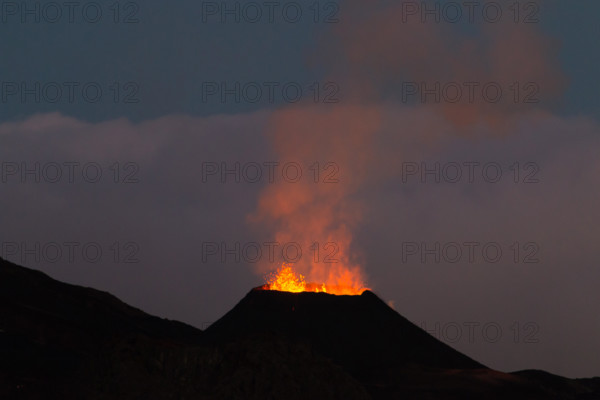 Ile de la reunion island Piton de la fournaise volcano eruption with lava flow and steam at night