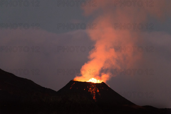 Ile de la reunion island Piton de la fournaise volcano eruption with lava flow and steam at night