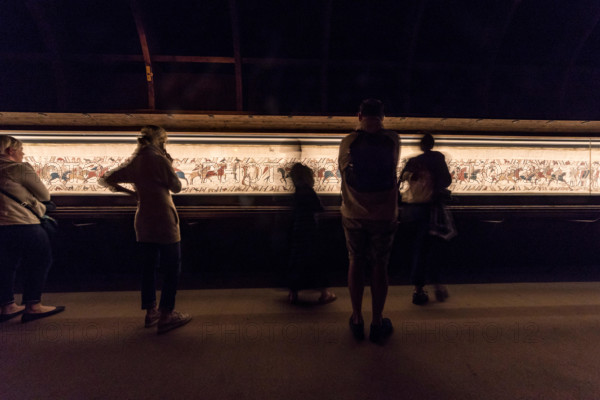 Bayeux, France. Visitorswalk past the famous tapestry (Tapisserie) of Bayeux,1000 year old carpet telling the story of the Norman conquest of England