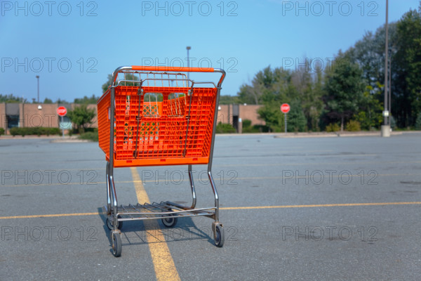 Horizontal shot of an orange shopping cart isolated on a parking lot at the mall