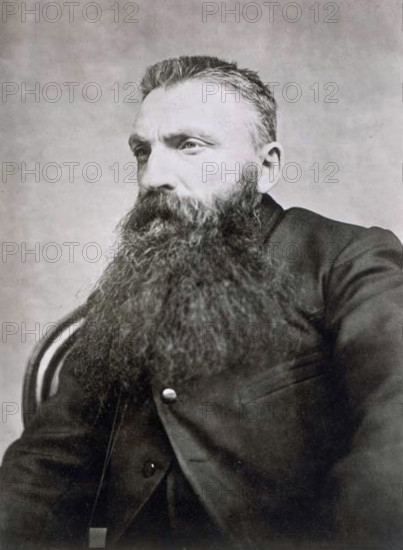 This photograph by Adolphe Braun, taken around 1889, shows the renowned sculptor Auguste Rodin with a crew cut hairstyle. It captures the artist in a personal moment, showcasing his distinctive look during the late 19th century.