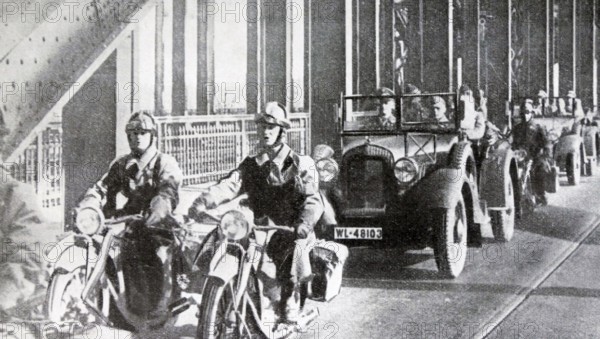 Black and white photo of the German troops crossing the Rhine River in cars and on motorcycles to enter Cologne, March 1936.
