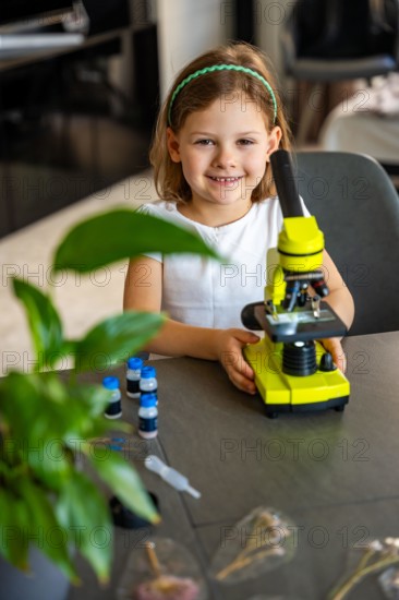 Portrait of little girl with green microscope. Concept of curiosity and early scientific exploration