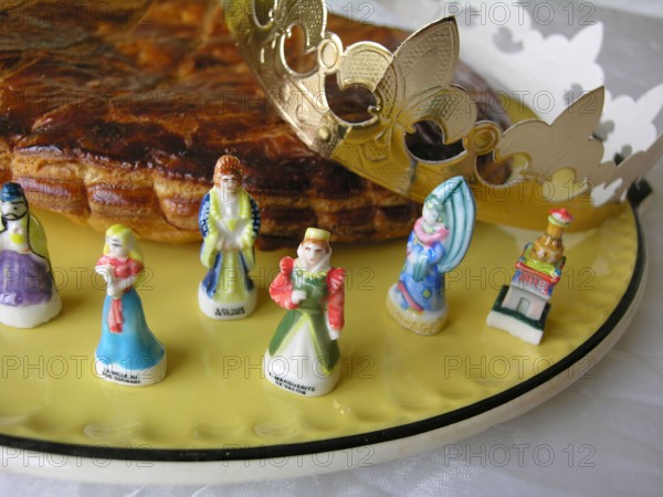 French galette des rois cake with small figurines and a crown to celebrate Epiphany in France