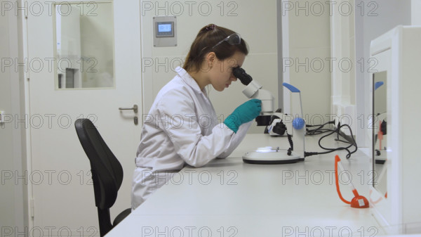 Doctor woman working a microscope. Female scientist looking through a microscope in lab. Student girl looking in a microscope, science laboratory concept