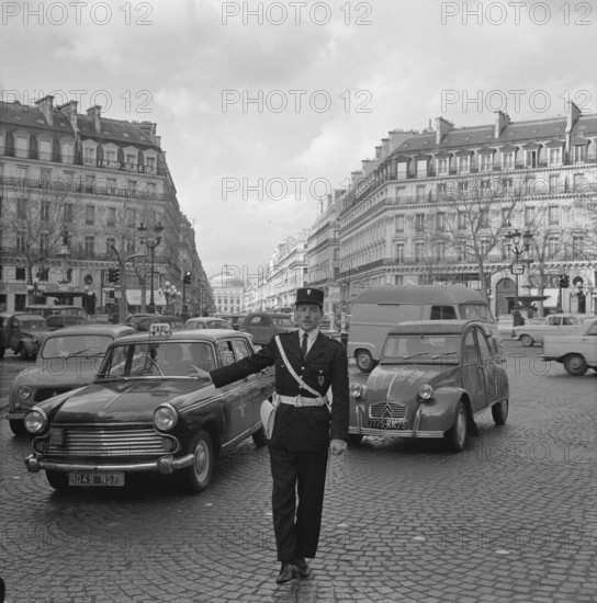 Pariser Bilder [The street life of Paris] Description: Agent regulates traffic Date: 1965 Location: France, Paris Keywords: cars, street images, traffic police