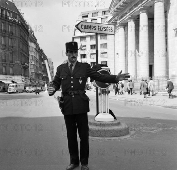Pariser Bilder [The street life of Paris] Description: Agent regulates traffic in the Rue du Faubourg-Saint-Honoré in front of the church of St. Philippe du Roule near the Champs Elysees Date: 1965 Location: Champs Elysées, France, Paris Keywords: church buildings, street statues, traffic police, columns