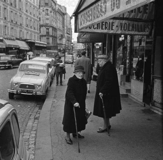 Pariser Bilder [The street life of Paris] Description: Elderly women in front of a store with meat and poultry in the Rue Lepic Date: 1965 Location: France, Paris Keywords: elderly, street sculptures, shops