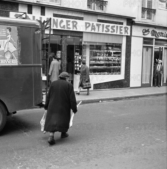 Pariser Bilder [Paris Street Life]  Customers at the entrance of a (pastry) bakery Date: 1965 Location: France, Paris Keywords: bakers, groceries, bread, street statues, shops