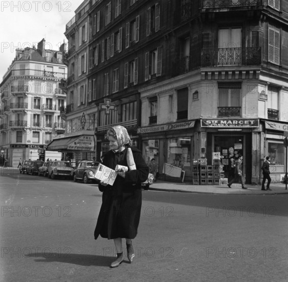 Pariser Bilder [The street life of Paris]  Woman crossing with messages in her hands Date: 1965 Location: France, Paris Keywords: groceries, bread, street sculptures, shops