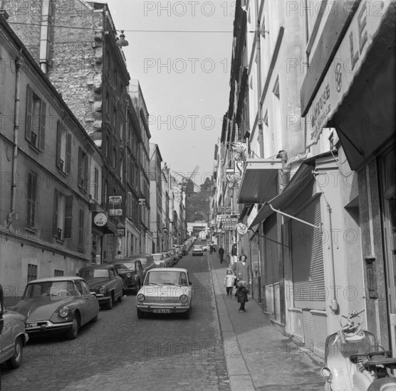 Pariser Bilder [The street life of Paris]  Rue Lepic in Montmartre, with Le Moulin de la Galette at the end of the street Annotation: Le Moulin de la Galette was a popular dance venue and figures on paintings by Vincent van Gogh, Henri Toulouse-Lautrec, Pablo Picasso and Auguste Renoir Date: 1965 Location: France, Paris Keywords: windmills, street images