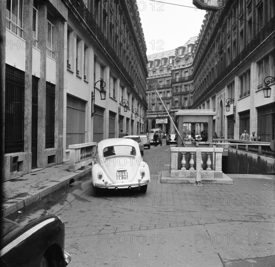 Pariser Bilder [Paris Street Life]  A Volkswagen Beetle at the barrier closing the private part of Rue Edouard VII Date: 1965 Location: France, Paris Keywords: Cars, security, controls, buildings, street footage