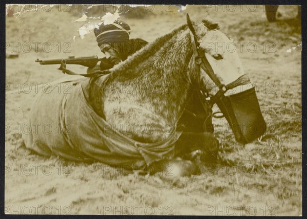 Description: [Algerian or Moroccan] cavalryman with rifle refuge behind a horse lying Annotation: The horse has a feed bag around his muzzle. Photo seems staged. Date: {1914-1918} Keywords: WWI, rifles, soldiers, horses