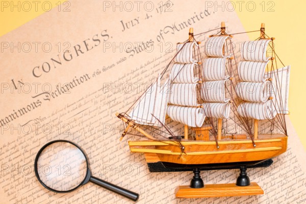 Ship made of wood and fabric handmade on the background of an excerpt from a copy of the document of 1776 on the signing of the independence of