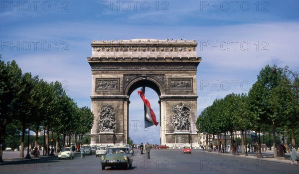 The Arc de Triomphe, summer 1963, with a huge French flag flying underneath it. Holiday in France. Vacances en France