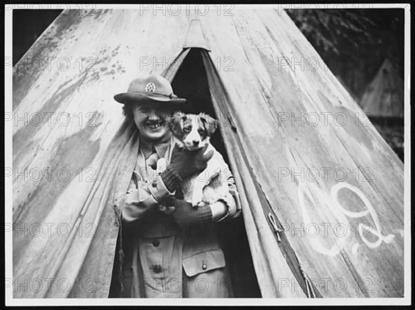 A worker at a World War I camp takes responsibility for the camp's mascot, reflecting the role of morale-boosting activities during wartime.